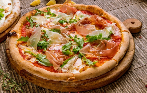 Пицца с рыбой и рукколой  на разделочной доске 