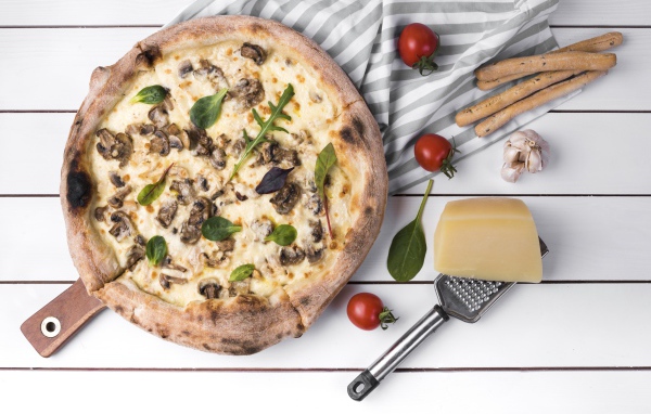 Пицца с грибами на столе с сыром и овощами
