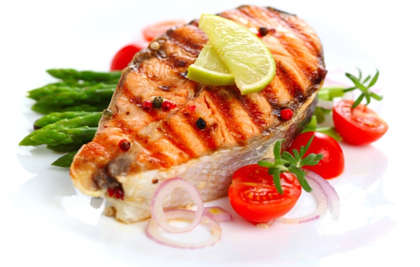 Кусок жареной рыбы с овощами на белом фоне 