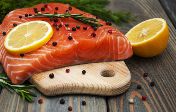 Кусок красной рыбы с лимоном и черным перцем