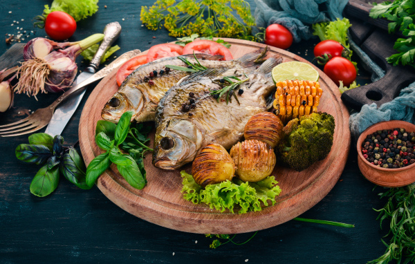 Baked fish on the cutting board with vegetables