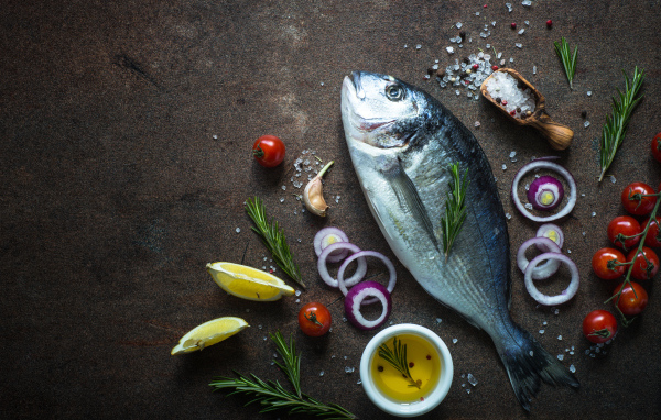 Свежая рыба на столе с овощами и специями 