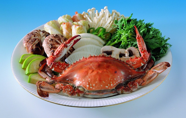 Морепродукты на тарелке с зеленью на голубом фоне