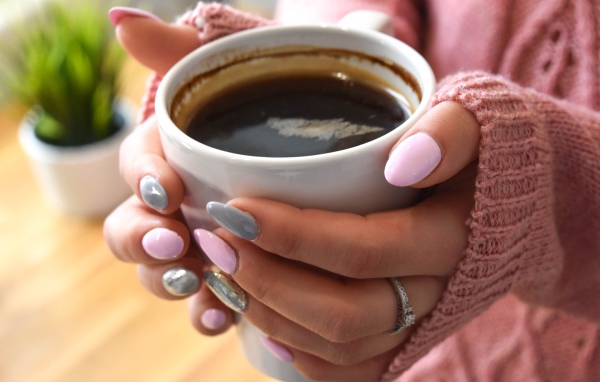 Чашка кофе в руках у девушки с маникюром