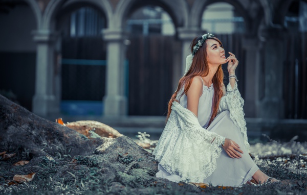 Мечтательная девушка азиатка в белом платье