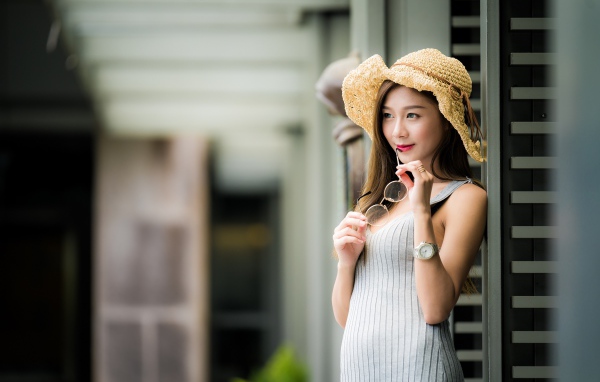 Девушка азиатка в шляпке с очками в руках 