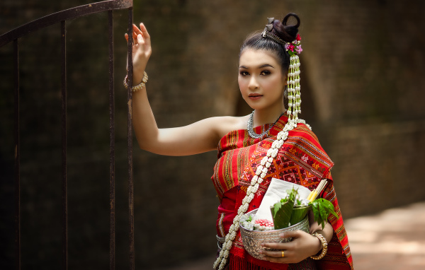 Девушка азиатка в костюме стоит у железных ворот