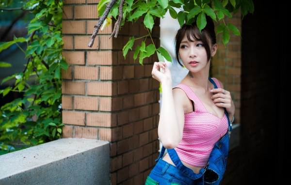 Молодая девушка азиатка у стены с зелеными листьями