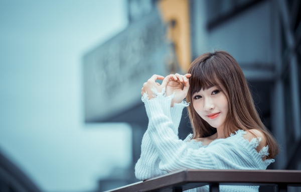 Молодая девушка азиатка в белом свитере на балконе
