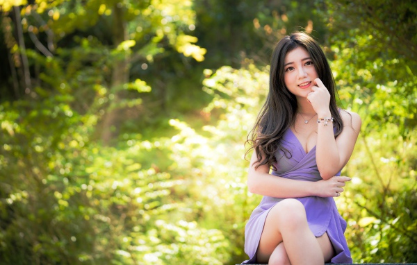 Молодая девушка азиатка сидит на лавке в парке