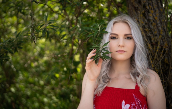 Красивая блондинка стоит у дерева 