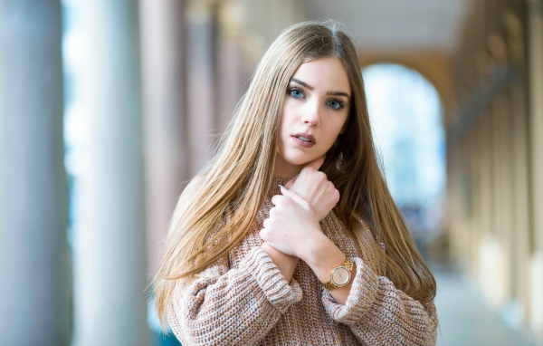 Красивая голубоглазая блондинка в теплом свитере с часами на руке