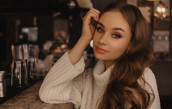 Красивая голубоглазая девушка в белом свитере в кафе