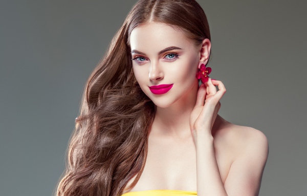 Красивая голубоглазая девушка с длинными волосами на сером фоне