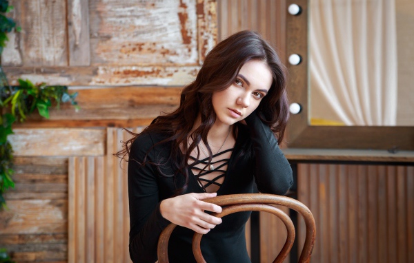 Красивая кареглазая девушка сидит на стуле