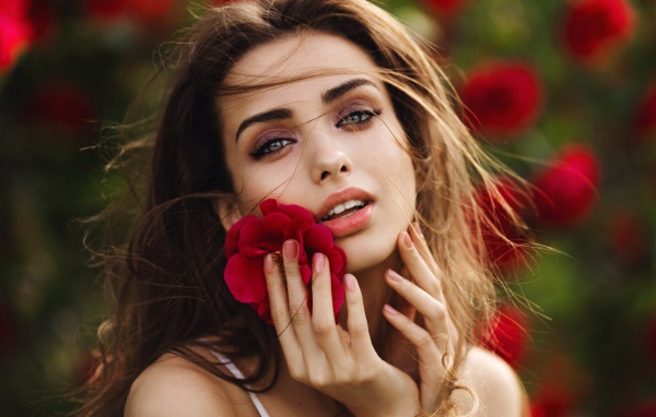 Красивая девушка шатенка с цветком у лица