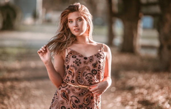 Красивая девушка в платье в лучах солнца летом