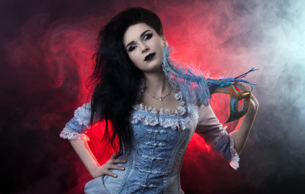 Красивая девушка в старинном платье с маской в руке