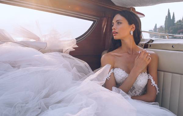 Красивая девушка в белом свадебном платье в машине