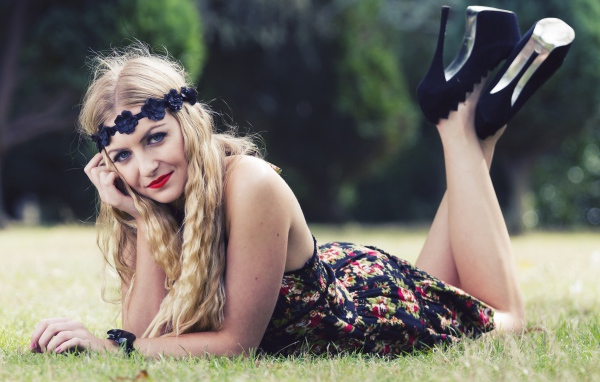 Красивая девушка в черных туфлях лежит на зеленой траве