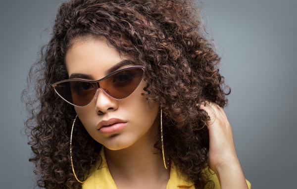 Красивая девушка в солнечных очках на сером фоне