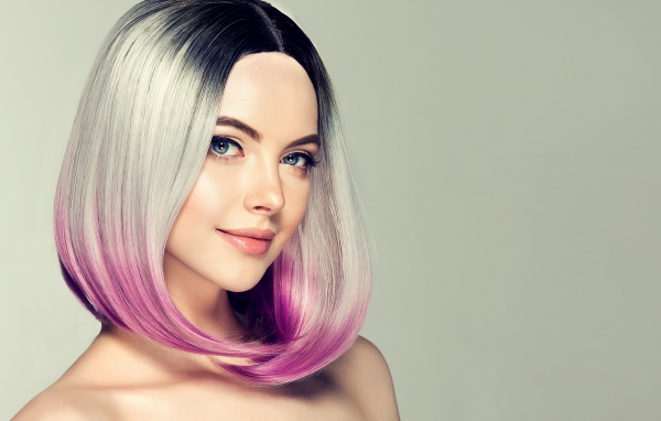 Красивая девушка с крашеными волосами на сером фоне