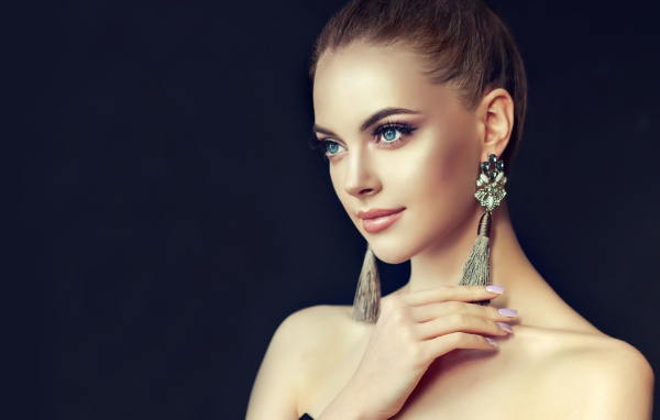 Красивая девушка с серьгами на черном фоне