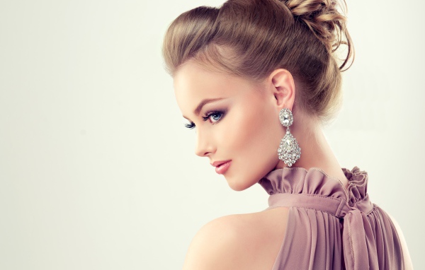 Красивая девушка с макияжем и прической на сером фоне