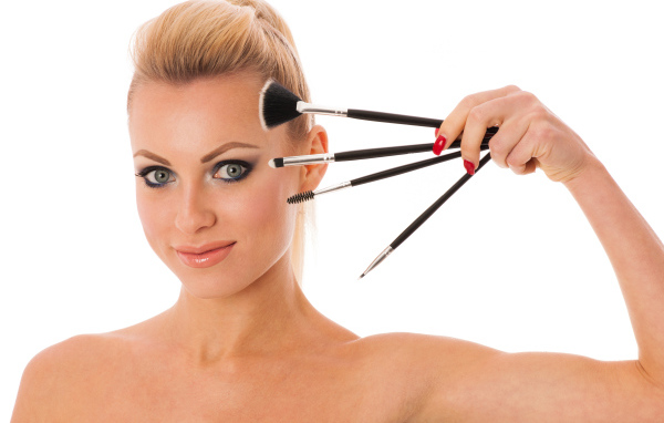 Красивая девушка с кистями для макияжа на белом фоне