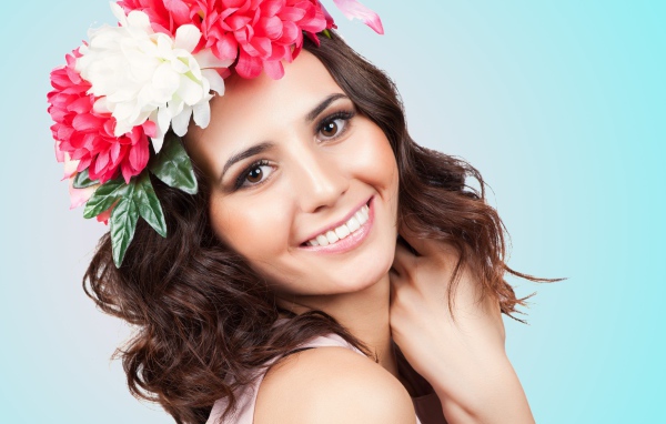 Красивая улыбающаяся девушка с венком на голове на голубом фоне