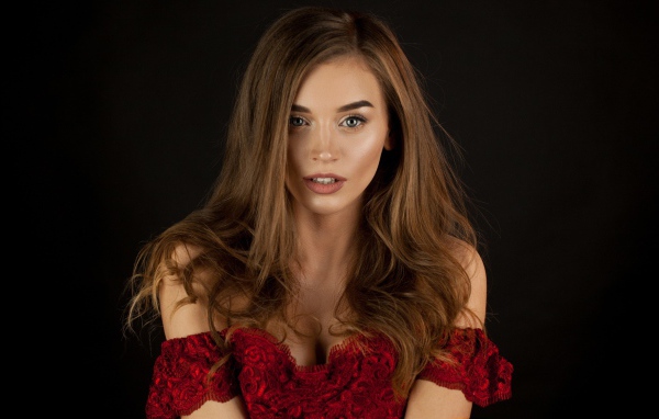 Красивая нежная длинноволосая шатенка в красном платье на черном фоне