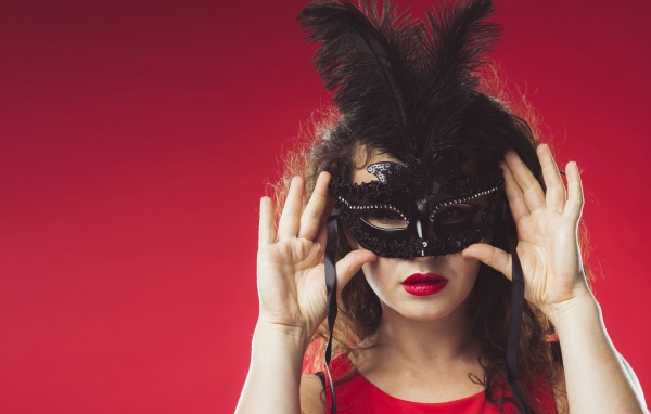 Красивая женщина в черной маске на красном фоне