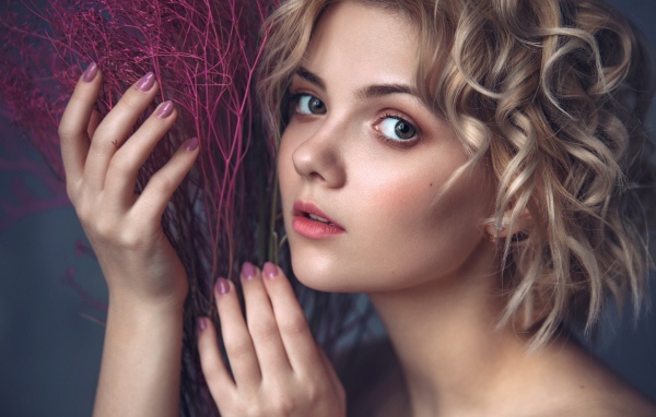 Красивая молодая блондинка с красным растением в руках