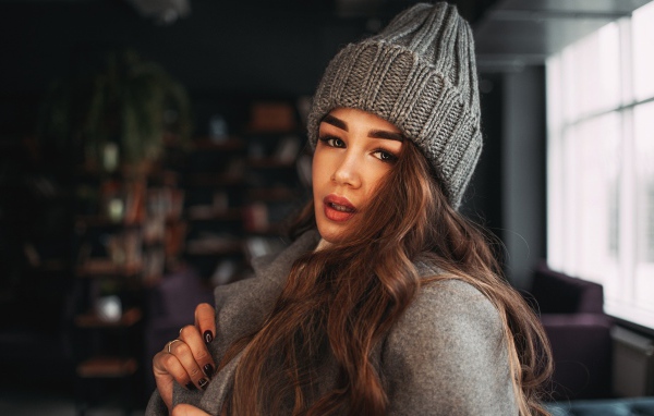 Красивая молодая девушка в пальто в вязаной шапке
