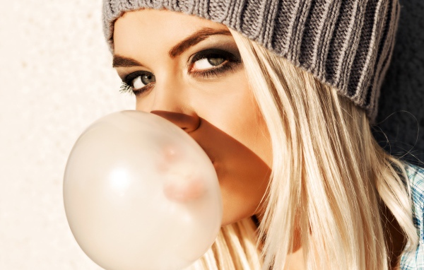 Девушка блондинка с жвачкой во рту крупным планом