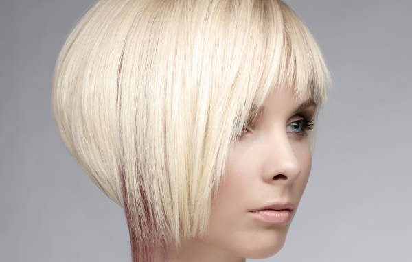 Голубоглазая девушка блондинка с короткой стрижкой на сером фоне