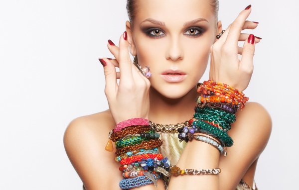 Кареглазая девушка с браслетами на руках на белом фоне