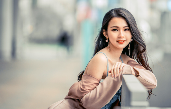 Очаровательная девушка азиатка сидит на лавке