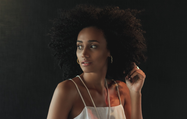 Темнокожая девушка с красивыми волосами на сером фоне