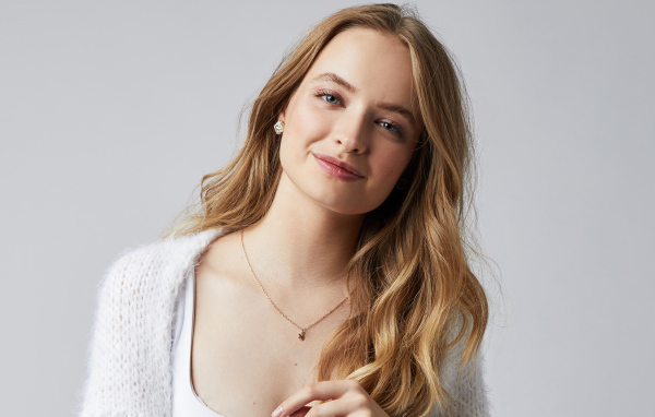 Нежная улыбающаяся голубоглазая девушка на сером фоне