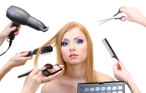 Девушке делают макияж и прическу на белом фоне