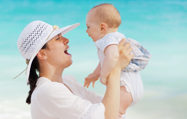 Девушка в белой шляпе с грудным ребенком в руках