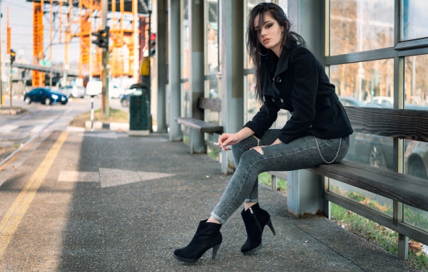 Девушка неформалка сидит на автобусной остановке