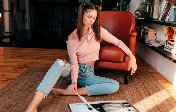 Девушка читает журнал на полу у кожаного кресла