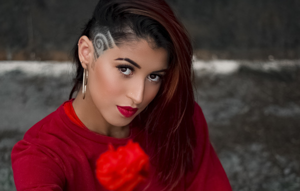 Девушка со стрижкой держит розу в руке