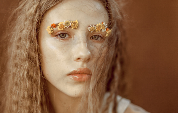 Девушка с цветами на бровях крупным планом