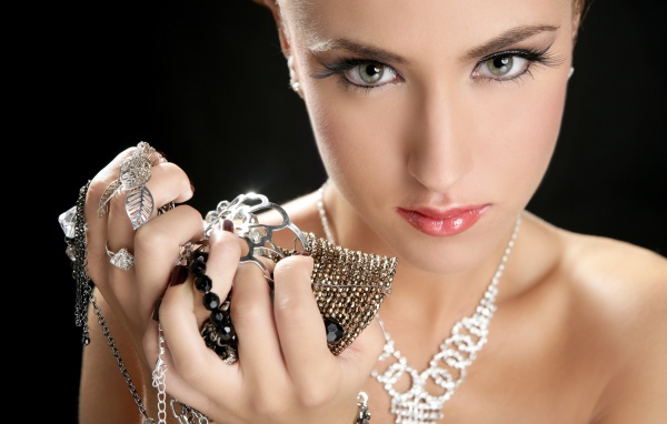 Девушка с длинными ресницами держит драгоценности в руке