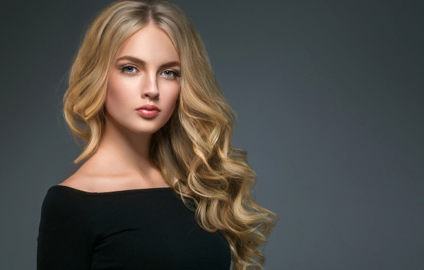 Длинноволосая блондинка с голубыми глазами на сером фоне