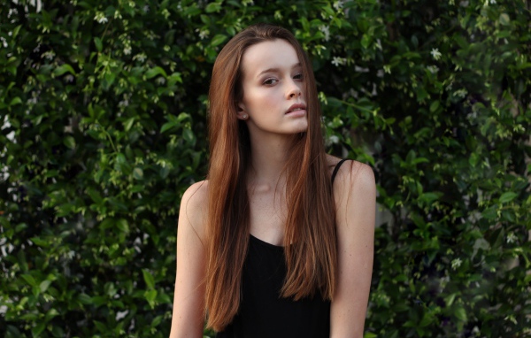 Длинноволосая шатенка на фоне зеленых зарослей