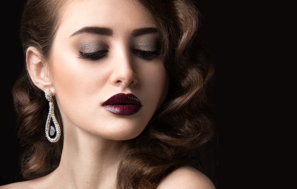 Длинноволосая девушка с ярким макияжем на черном фоне